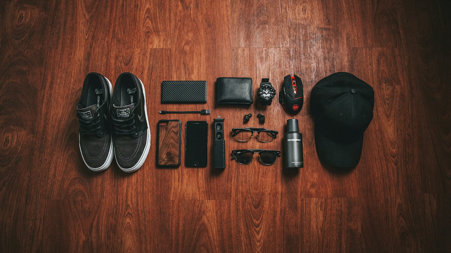 Men's everyday carry essentials arranged on a wooden surface.