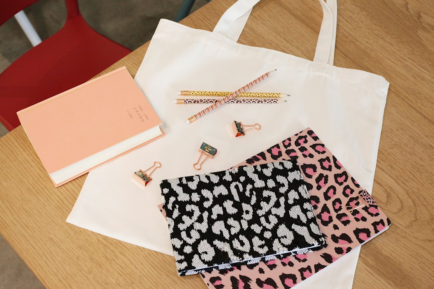 Creative stationery laid out on a wooden table with a red chair.