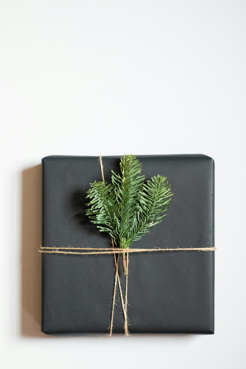 Gray gift box with twine and evergreen sprigs.