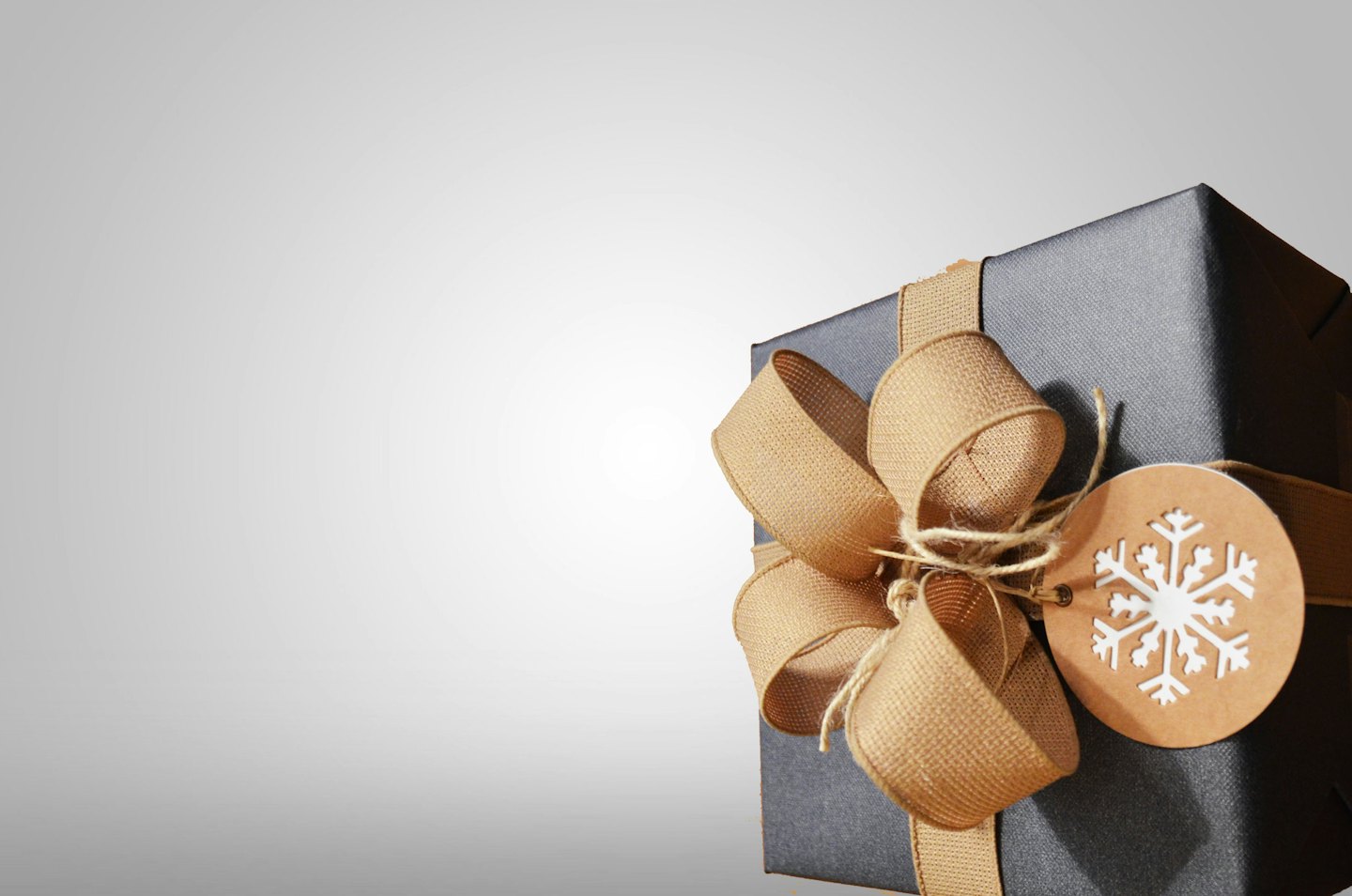 Dark grey gift box with beige ribbon and snowflake tag.